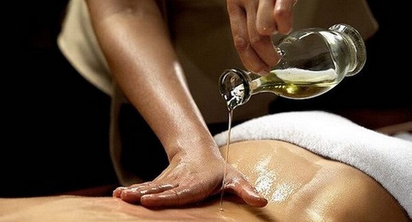 Professional Ayurvedic massage treatment using warm herbal oils demonstrating traditional Abhyanga techniques